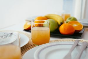 Bright and fresh breakfast setup featuring orange juice and a variety of fruits on a neatly arranged table.