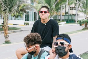 Young men with sunglasses and masks hanging out on a street in sunny Cartagena, Colombia.