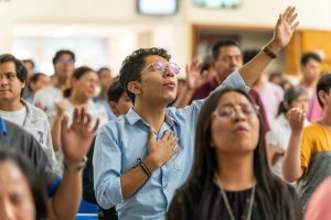 A congregation participates in a spiritual ceremony, raising hands in prayer and devotion in Mexico City.