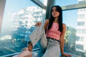 Young woman posing confidently by a window with city view in Buenos Aires.