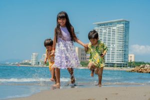 Joyful children playing by the sea on a sunny summer day, creating family memories.