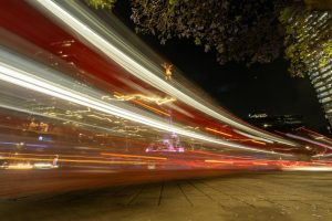 Vivid light trails surround the Angel of Independence in bustling Mexico City at night.