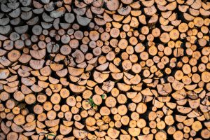 Textured background of pile of rough firewood with shabby uneven surface in daytime