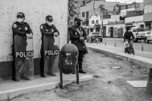 Police officers in masks standing on a city sidewalk, ensuring public safety.