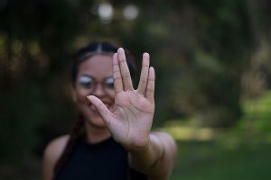 A woman performing the Vulcan salute with an outstretched hand, standing outdoors.