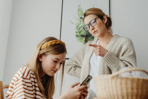 A mother scolds her teenage daughter for excessive phone use at home.