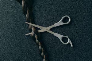 ¿Es cierto que cortarse el cabello después de comer es malo? Artistic display of scissors poised to cut a braid against a dark textured backdrop.