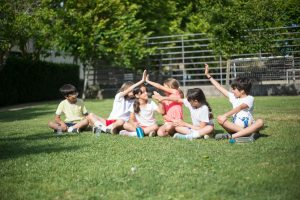 A group of children sitting and interacting on a sunny day in Portugal.