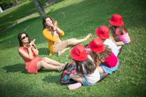 Two adults and children playing together on grass in a sunny Portuguese park.