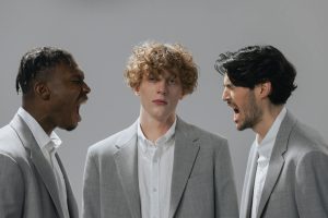 Three men in office attire expressing emotion in a corporate setting.