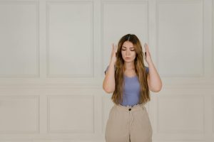 Young woman signing with eyes closed, expressing communication through sign language.