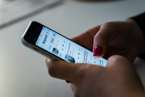 Person holding a smartphone and browsing social media, showcasing touchscreen interaction.