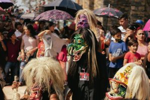 Colorful Mexican festival featuring traditional masks and a diverse crowd enjoying the celebration.