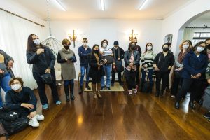 A large group of adults wearing face masks gathered indoors, emphasizing pandemic safety measures.