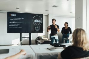 Two colleagues giving a dynamic business presentation in a modern office environment, engaging their audience.