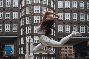 A young woman performs an energetic dance leap in the iconic Sprinkenhof courtyard, Hamburg.