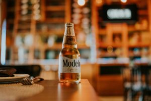 Close-up of a Modelo beer bottle on a wooden table, capturing the essence of a cozy restaurant ambiance.