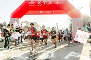 Runners participate in a marathon under a red arch in Santa María Atarasquillo, Mexico.