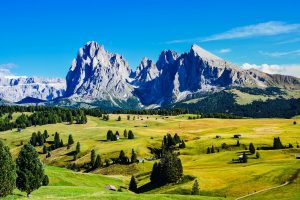 Breathtaking view of sunlit Dolomites in the Italian countryside, showcasing lush greenery and majestic peaks.