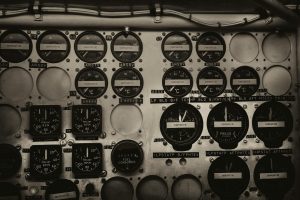 Detailed view of a vintage aircraft cockpit panel with various gauges and dials in black and white.