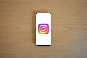 A smartphone with the Instagram logo on display, placed on a wooden surface. Perfect for technology and social media themes.