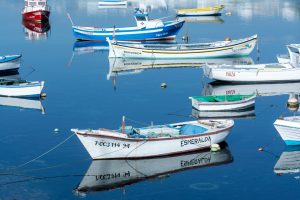 Serene view of colorful boats anchored at Arrecife harbor in Spain, reflecting on calm waters. Perfect for travel inspiration.