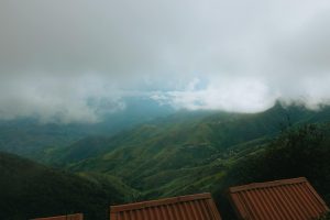 A breathtaking view of mist-covered mountains and lush green valleys, showcasing nature's tranquility.