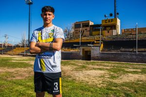 Confident young soccer player posing on the field during a bright day.