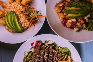 Three flavorful dishes featuring seafood and avocado, plated creatively for a delightful meal.