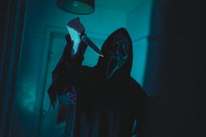 Dark, eerie scene with a masked figure holding a knife, evoking horror film vibes.