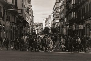 A bustling city street in Madrid with people crossing. Urban lifestyle captured in sepia tones.