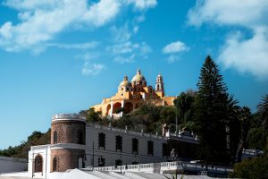 Beautiful view of the yellow-domed Iglesia de Nuestra Señora in Cholula, Mexico against a bright blue sky.