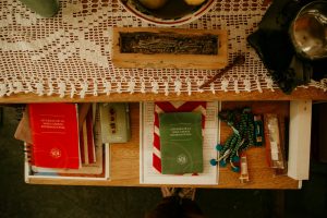 Religious books and items on a wooden table with a lace tablecloth.