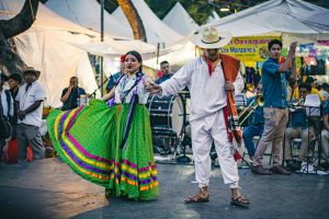 Mexican dancers performing traditional folk dance in colorful attire at a cultural event in Mexico City.