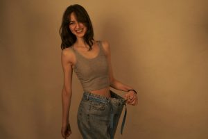 Joyful woman shows success in weight loss by wearing loose jeans. Healthy lifestyle concept.