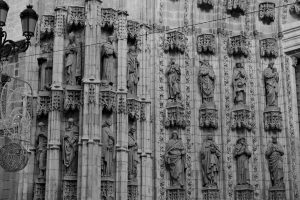 Black and white photo of Seville Cathedral's detailed Gothic facade with statues.