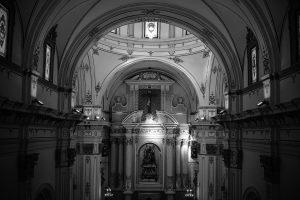 Black and white photo capturing the ornate interior of a basilica in Dolores, Spain, showcasing its architectural details.