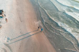 Serene aerial shot of Padre Island beach with waves and people walking at sunset.