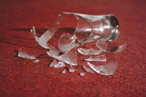 Close-up of broken glass scattered on a red carpet, creating a dramatic and moody scene.