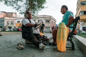 Two men engaging in conversation in a lively outdoor setting in Trujillo, Peru.