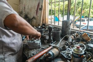 Mechanic organizing auto parts in a busy workshop, surrounded by tools and equipment.