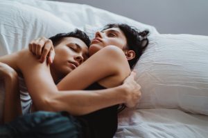 A tender moment of an affectionate couple embracing in bed, capturing warmth and intimacy.