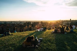 Enjoy a serene sunset picnic on a grassy hill overlooking the vibrant city skyline.