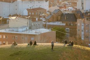 People enjoying sunset on a hill with view of Madrid cityscape.