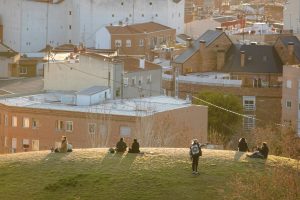A serene scene of people sitting on a hill, with view of buildings in Madrid, Spain during golden hour.
