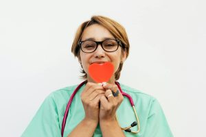 Doctor holding a red heart symbol, promoting healthcare compassion.