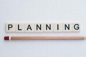 Overhead shot of letter tiles spelling 'planning' with a pencil on graph paper.