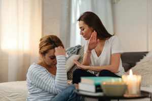 Two women in a tense emotional exchange in a cozy home setting.