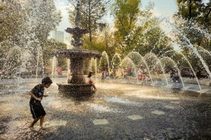 Children joyfully play in a fountain at a park in Mexico City, enjoying water splashes on a sunny day.