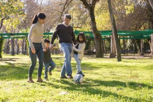 A family plays soccer together in a sunny park, enjoying quality time outdoors.
